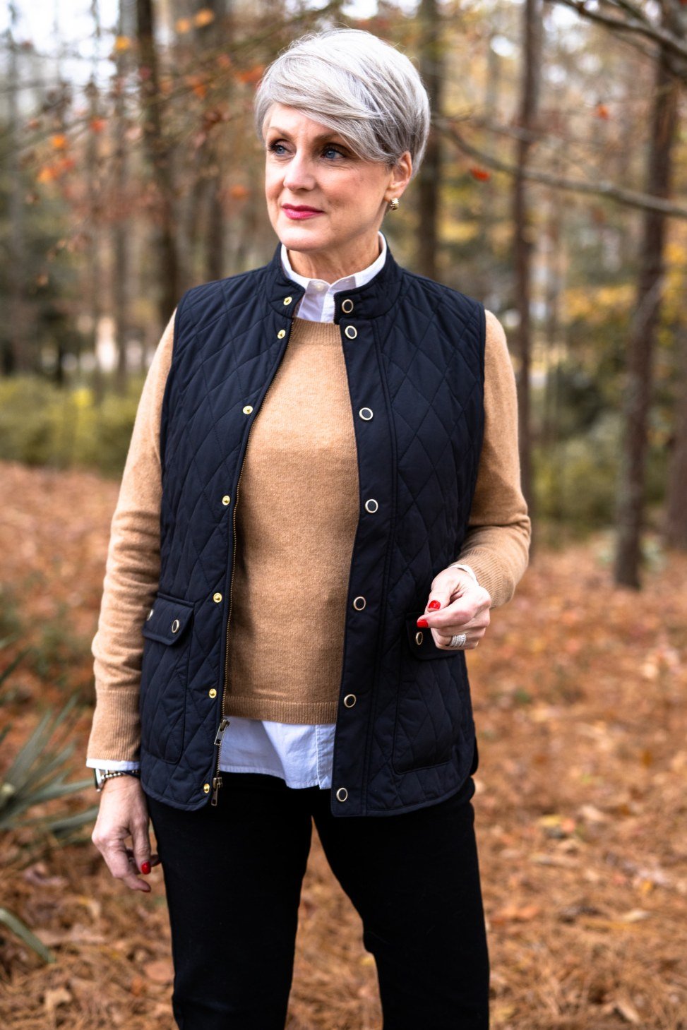 Fall turtleneck outfit for women over 50: mustard turtleneck with black quilted vest, autumn woods