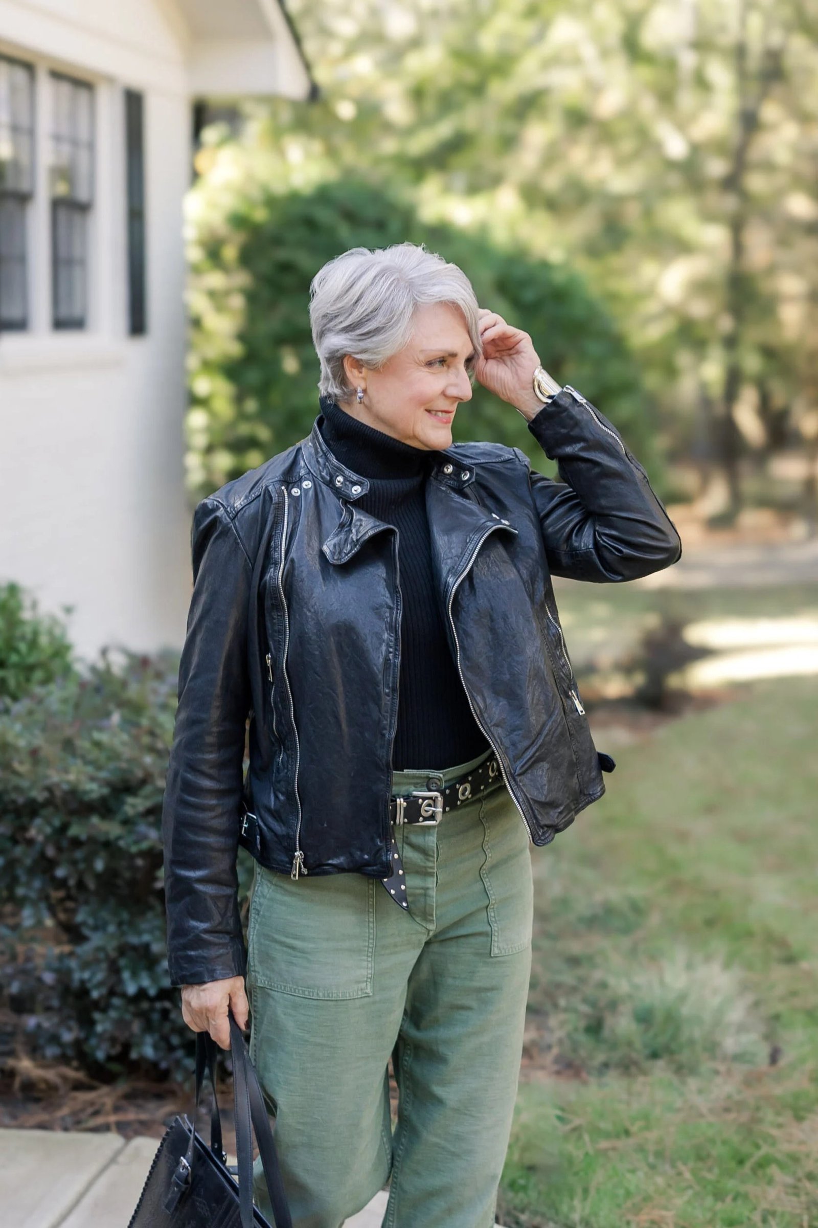 Fall turtleneck outfit for women over 50: black turtleneck with black moto jacket, green trousers