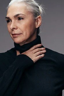 Fall turtleneck outfit for women over 50: black turtleneck portrait, hand at neck, close-up