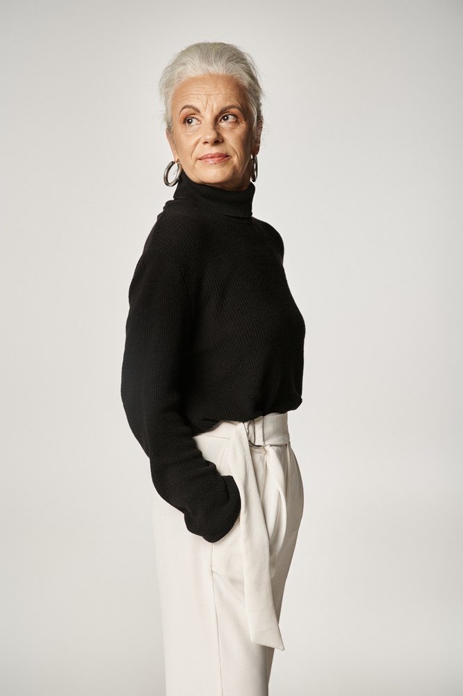 Fall turtleneck outfit for women over 50: black turtleneck with white wide pants, hoop earrings, studio