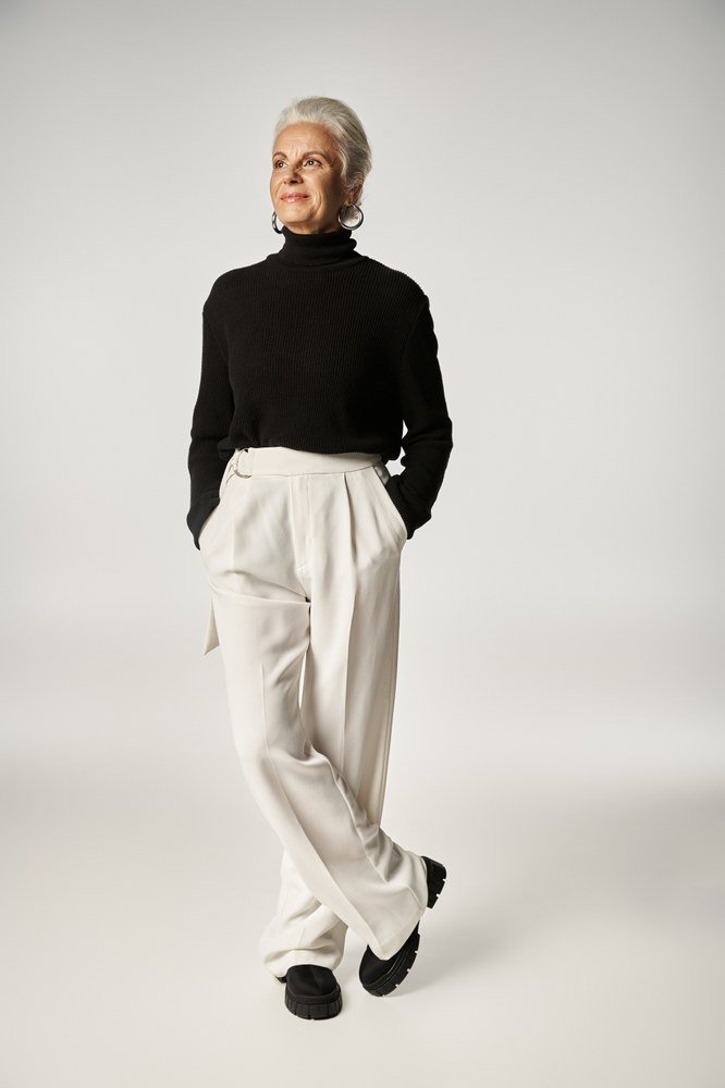 Fall turtleneck outfit for women over 50: black turtleneck with cream wide trousers, studio