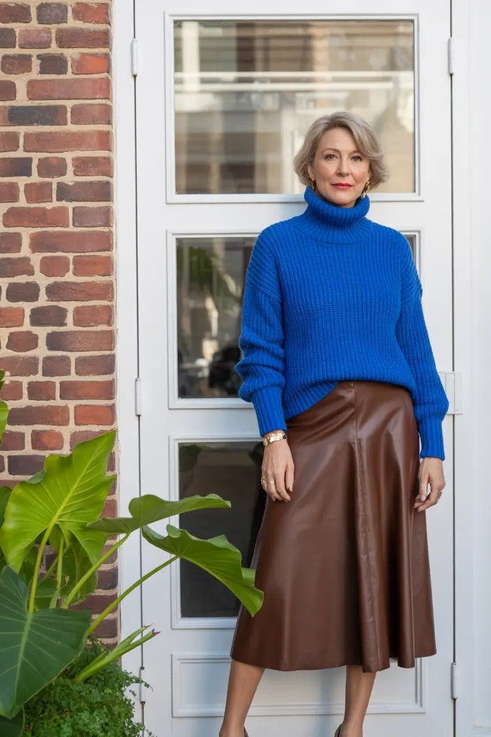 Fall turtleneck outfit for women over 50: royal blue turtleneck with brown leather midi skirt, doorway