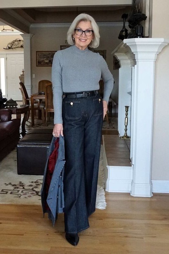 Fall turtleneck outfit for women over 50: gray turtleneck with dark jeans, living room