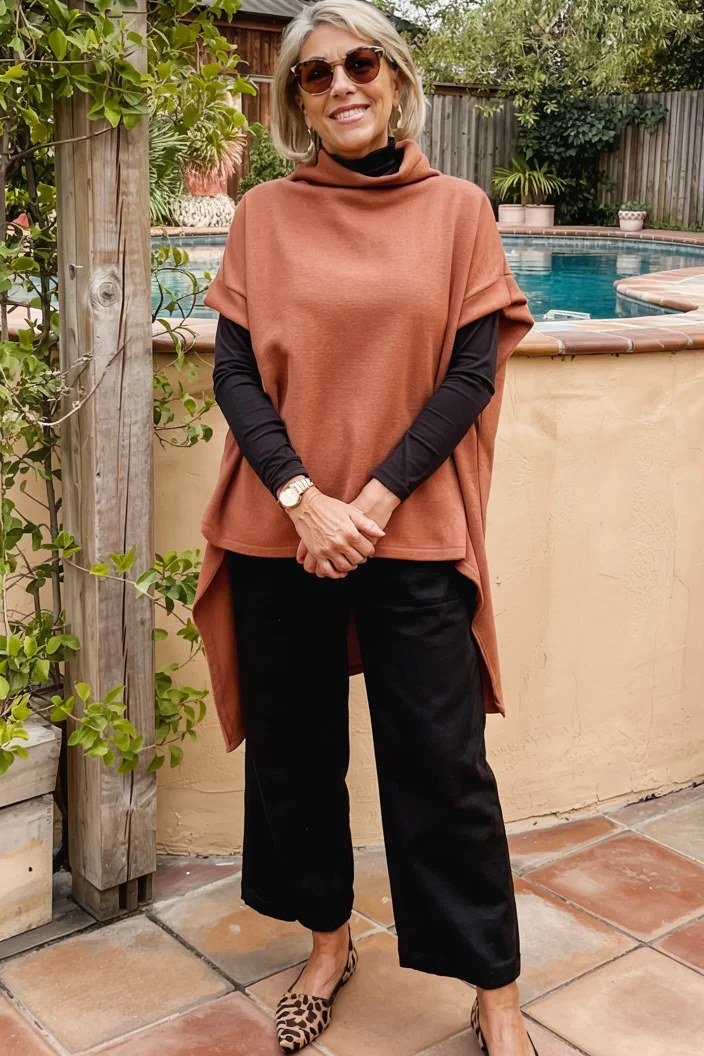Fall turtleneck outfit for women over 50: black turtleneck with rust poncho, garden