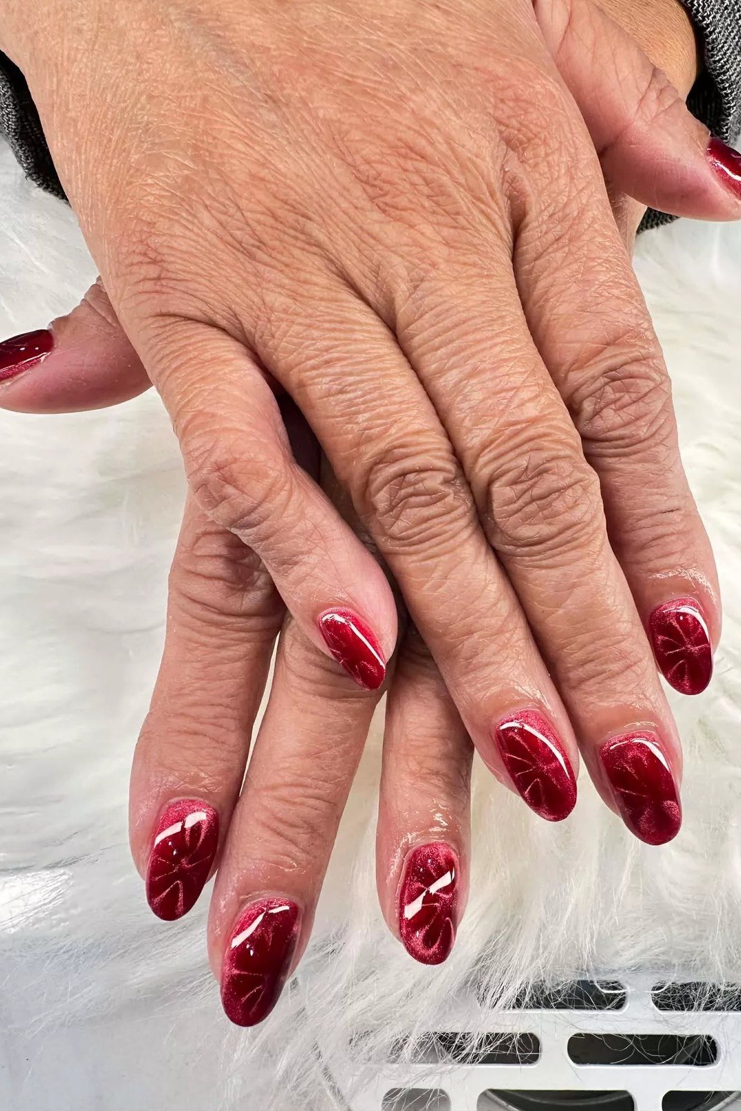 Red cat eye on mature hands - nail ideas for women over 40