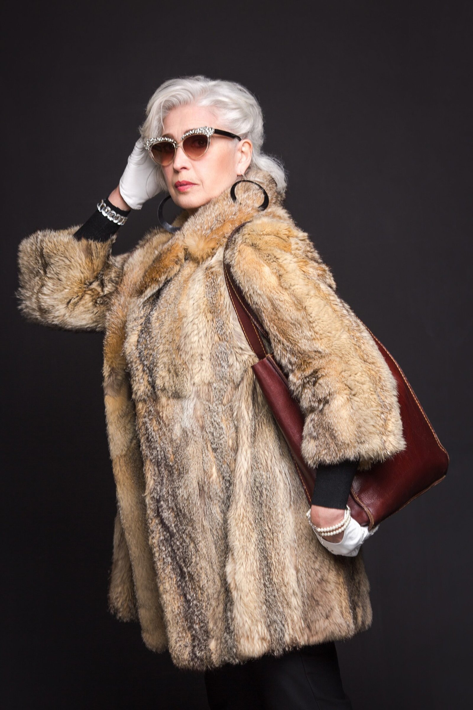 Winter outfit idea 2 for women over 60: tan fur coat with burgundy handbag and sunglasses