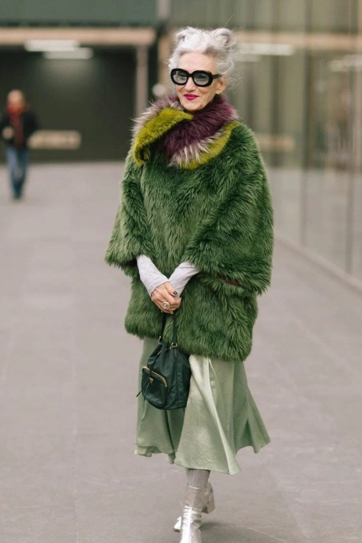 Winter outfit idea 4 for women over 60: green fur jacket with green midi skirt, street