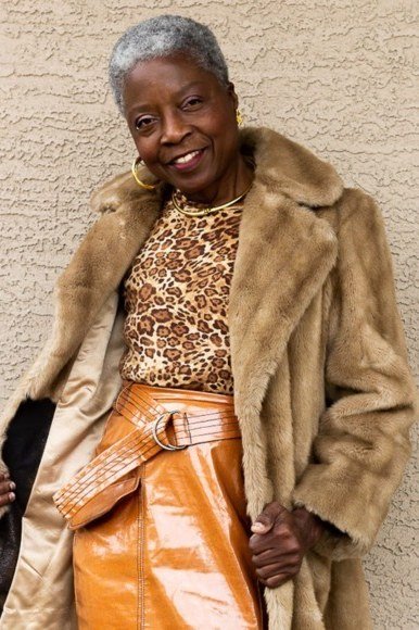 Winter outfit idea 5 for women over 60: tan fur coat with leopard top and orange satin skirt