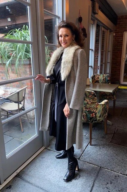 Winter outfit idea 6 for women over 60: grey fur-trim coat over navy dress