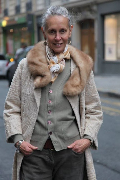 Winter outfit idea 11 for women over 60: grey fur-trim long coat with sage vest and trousers