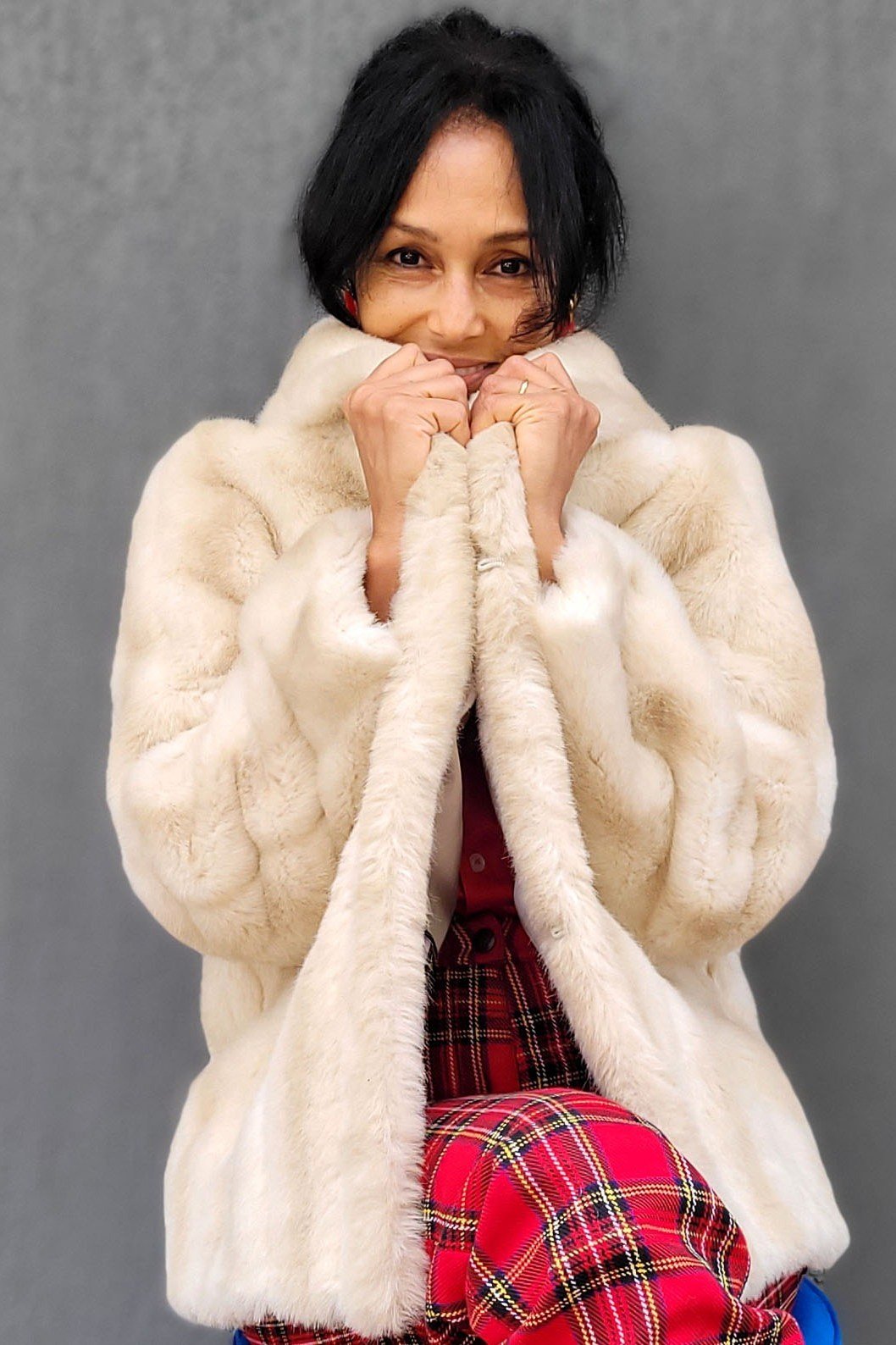 Winter outfit idea 12 for women over 60: cream fur jacket with red plaid skirt