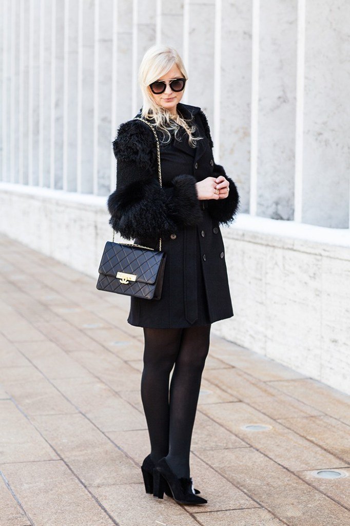 Winter outfit idea 13 for women over 60: black fur-trim coat with black dress and quilted bag