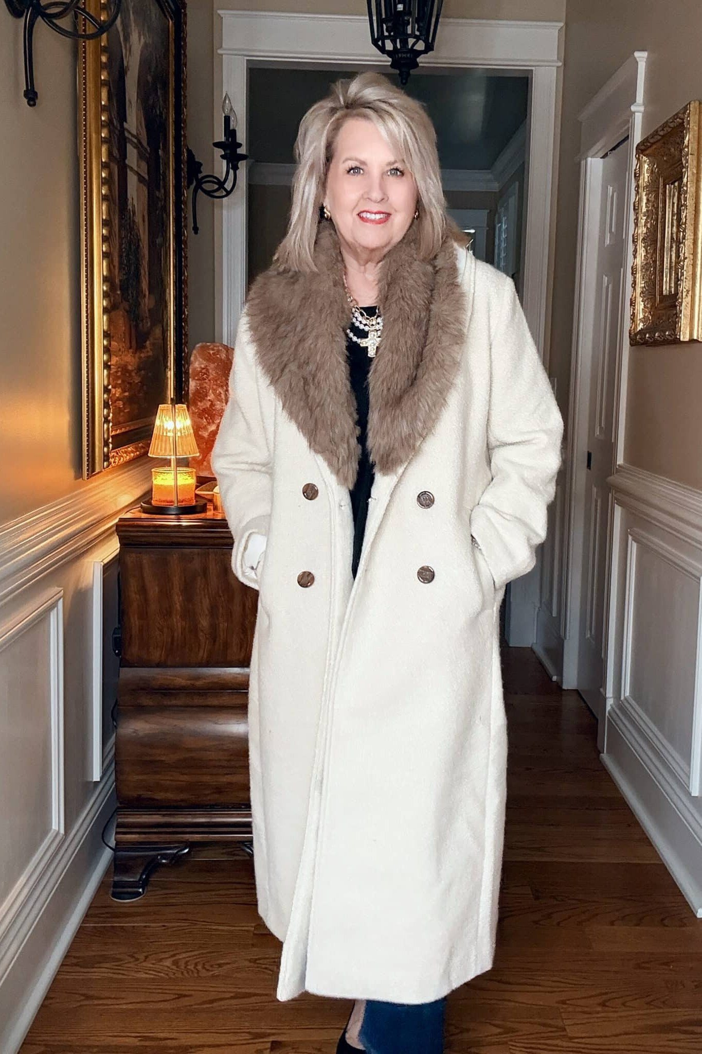 Winter outfit idea 15 for women over 60: white coat with brown fur collar, hallway