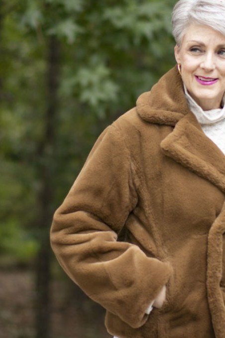 Winter outfit idea 27 for women over 60: camel shearling coat with white turtleneck, outdoor