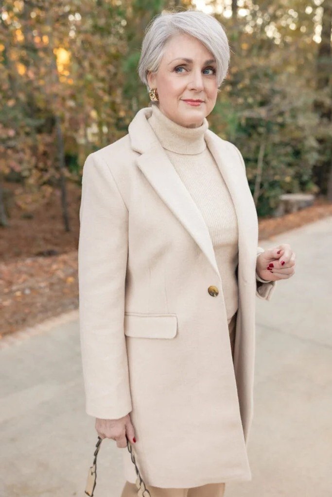 Winter outfit idea 39 for women over 60: cream coat with turtleneck, park