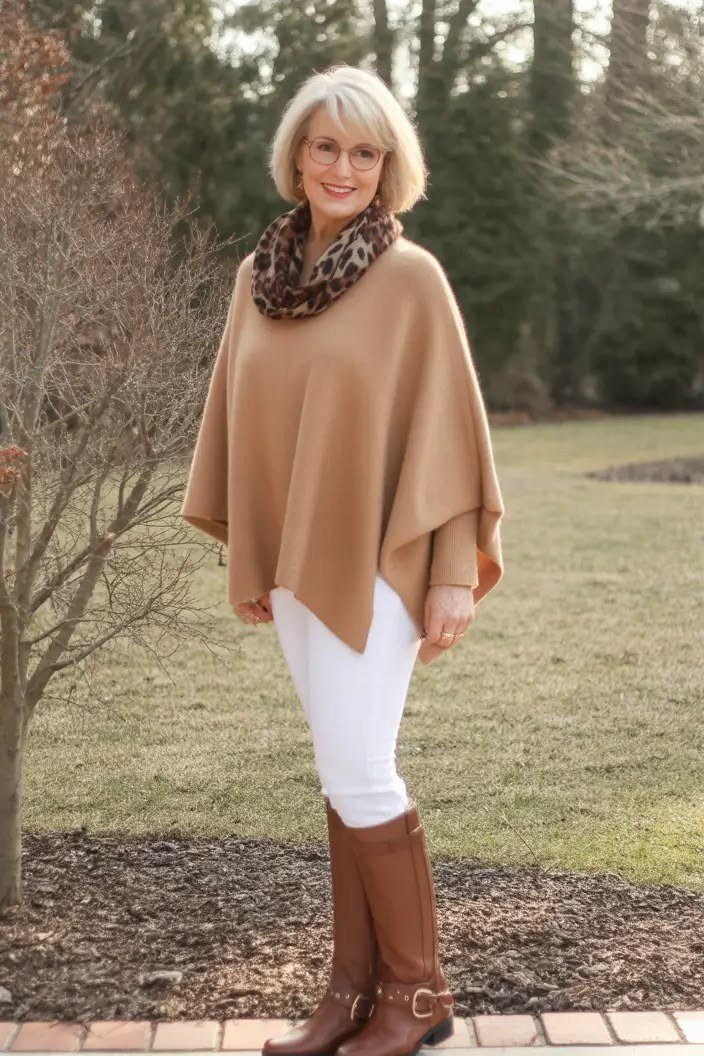 Winter outfit idea 51 for women over 60: camel poncho with white jeans and tan boots