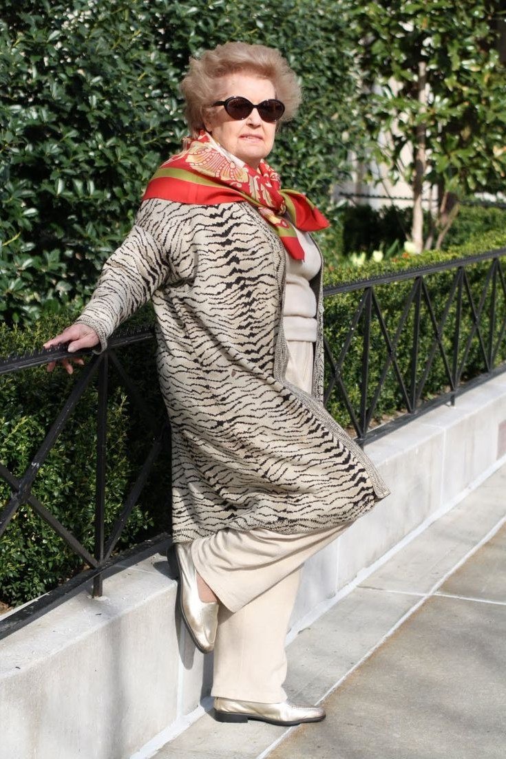 Winter outfit idea 53 for women over 60: animal print coat with red scarf, railing