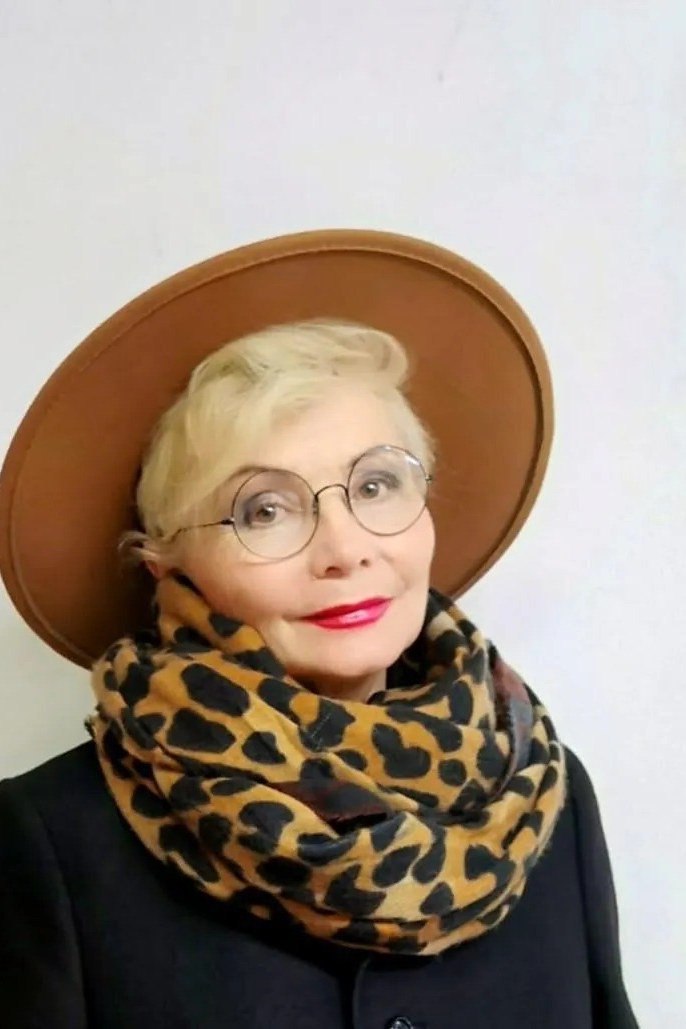 Winter outfit idea 56 for women over 60: black coat with wide-brim hat and leopard scarf