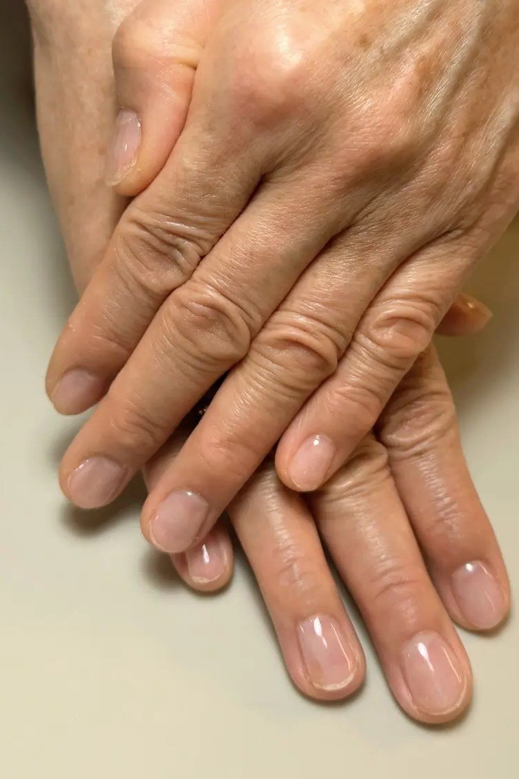 Sheer nude almond nails on mature hands for women over 50