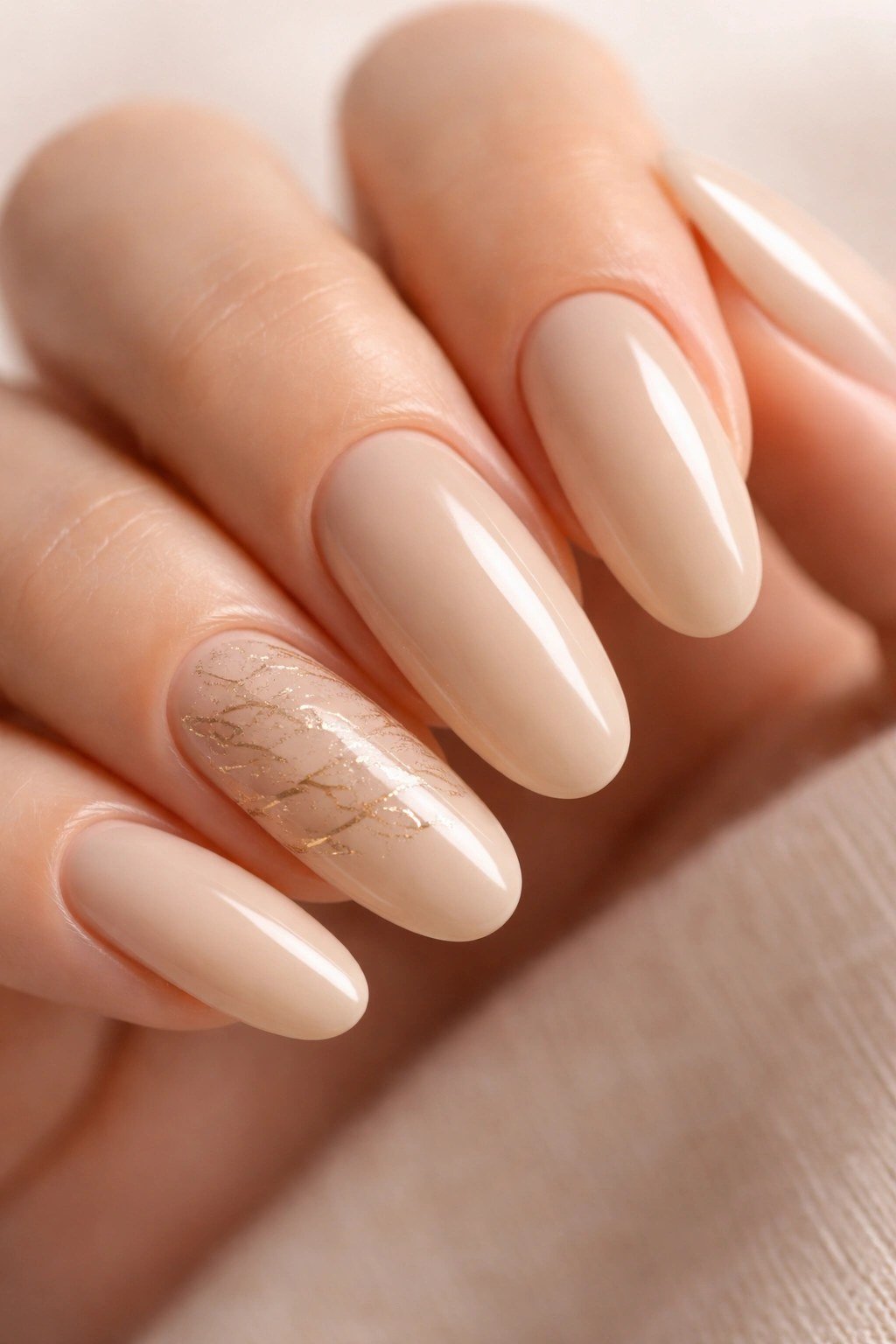Warm beige nude almond nails with gold marble accent for women over 50