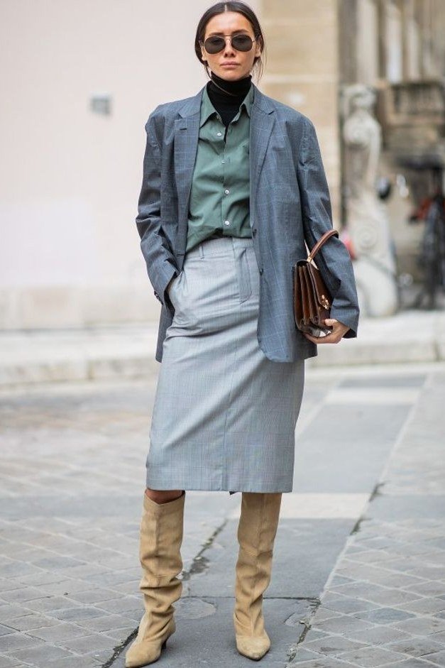 Woman over 60 wearing grey blazer with sage shirt, grey midi skirt and tan knee high boots
