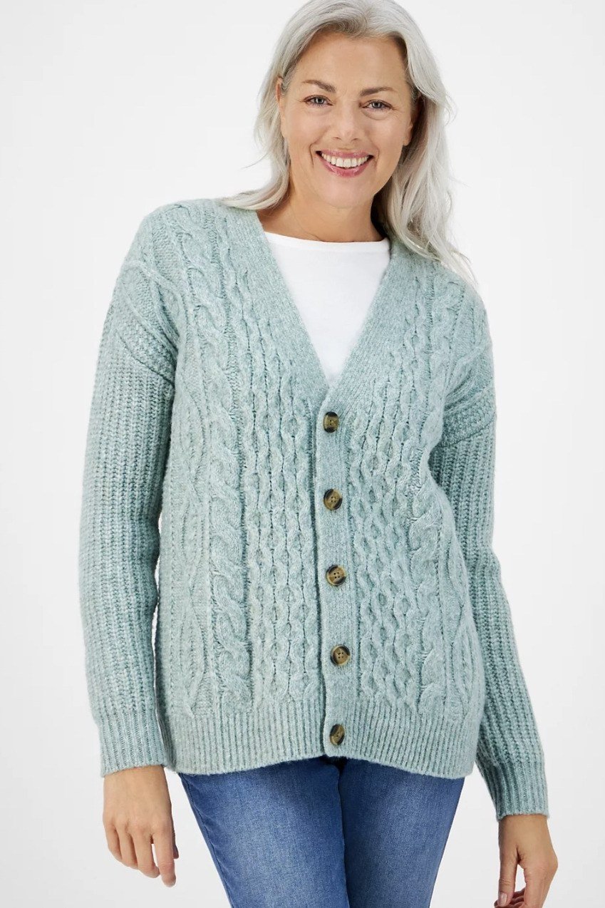 Woman wearing sage green cable knit cardigan with white top and blue jeans