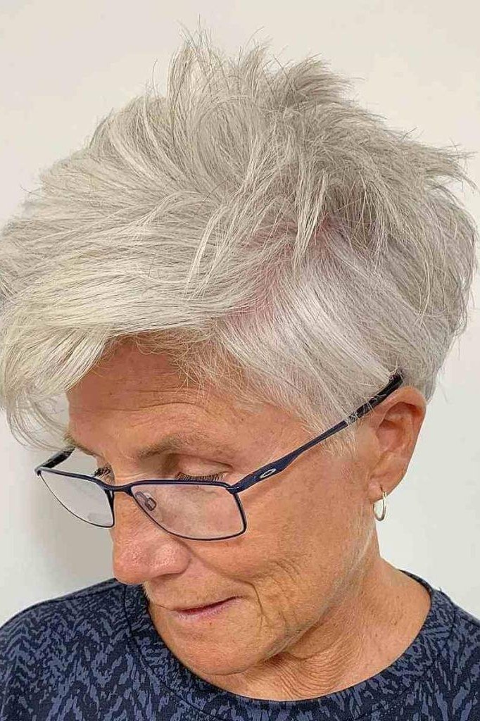 White spiky pixie, looking down, glasses, navy top - wash and wear haircut for women over 60