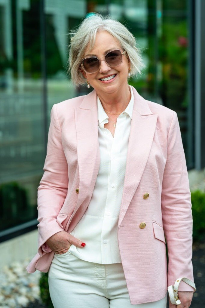 Pink blazer business casual outfit for women over 50 with white trousers