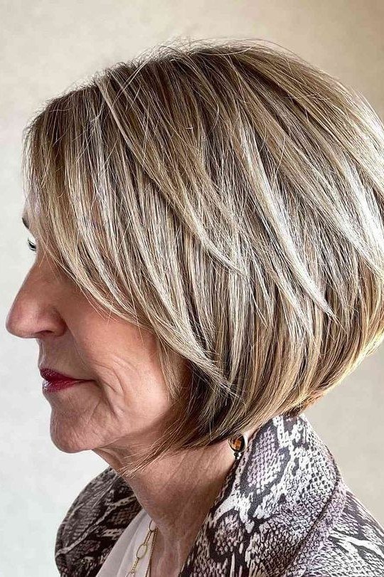 Blonde wedge with long face-framing front on a woman over 60, side view - wedge bob hairstyle