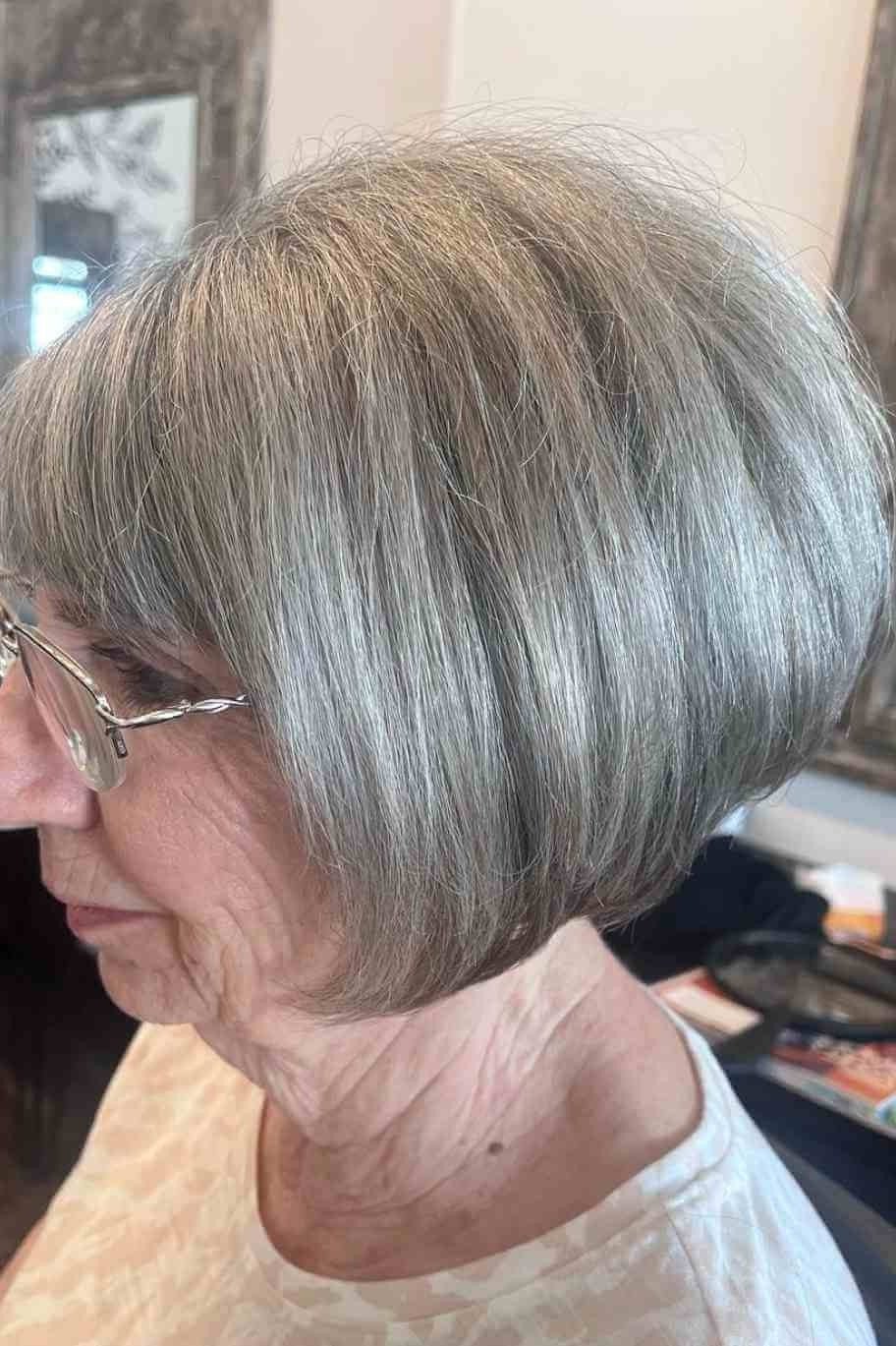 Silver wedge with glasses on a woman over 60, three-quarter view - wedge bob hairstyle