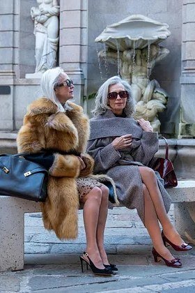 Winter outfit for women over 60: two women in faux-fur coats on bench