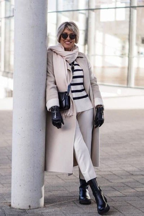Winter outfit for women over 60: light gray coat, striped top, white pants, black ankle boots