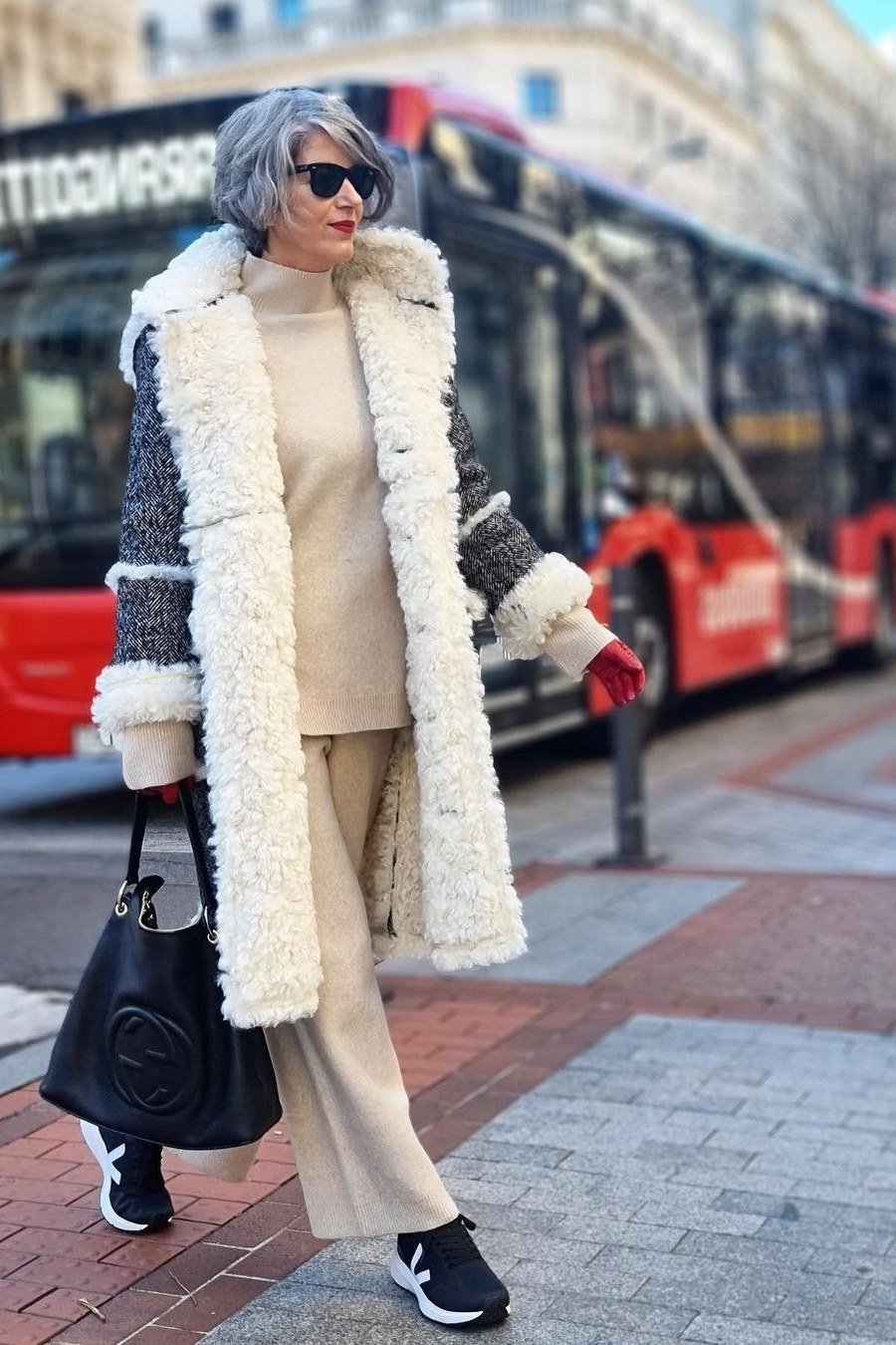 Winter outfit for women over 60: green faux-fur coat, sage satin skirt, silver boots, city
