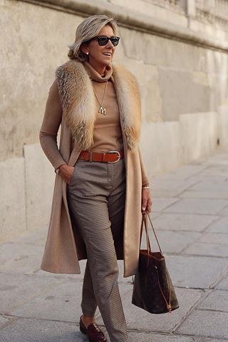 Winter outfit for women over 60: shearling-trim coat, cream set, black handbag, white sneakers