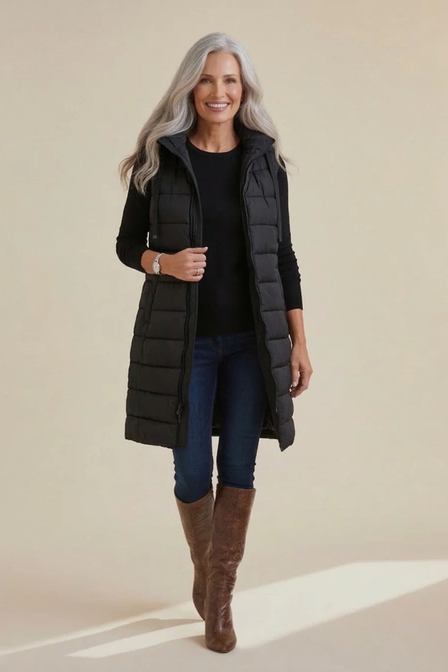Black Long Puffer Vest with Jeans and Tan Boots on a woman over 60, cozy winter casual outfit idea 46