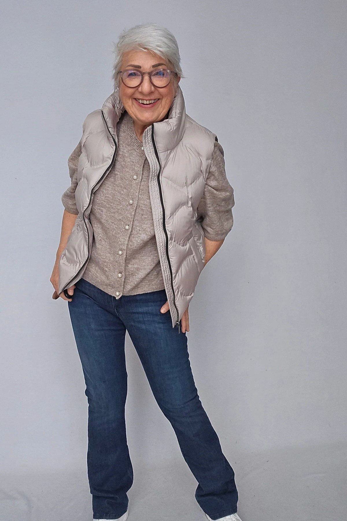 Beige Puffer Vest with Jeans and White Sneakers on a woman over 60, cozy winter casual outfit idea 47