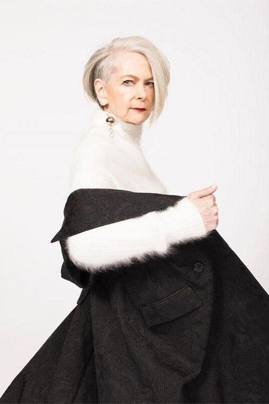 winter date night outfit for women over 60: black coat with white fur trim, studio shot