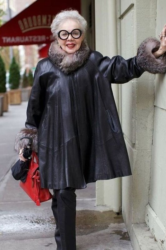 winter date night outfit for women over 60: black leather fur-trim coat with red handbag on the street
