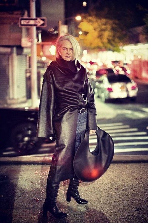 winter date night outfit for women over 60: burgundy leather coat with a black dress and boots at night