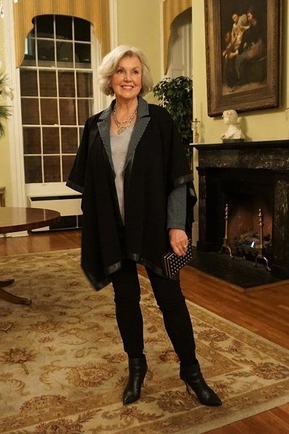 winter date night outfit for women over 60: black coat with boots in an elegant interior