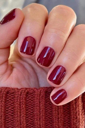 Deep red glossy short winter nails with rust sweater