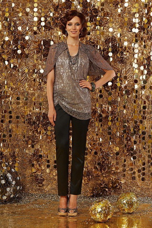 Woman in silver sequin top with black pants against gold disco-ball wall, party-ready New Year's Eve outfit for women over 60