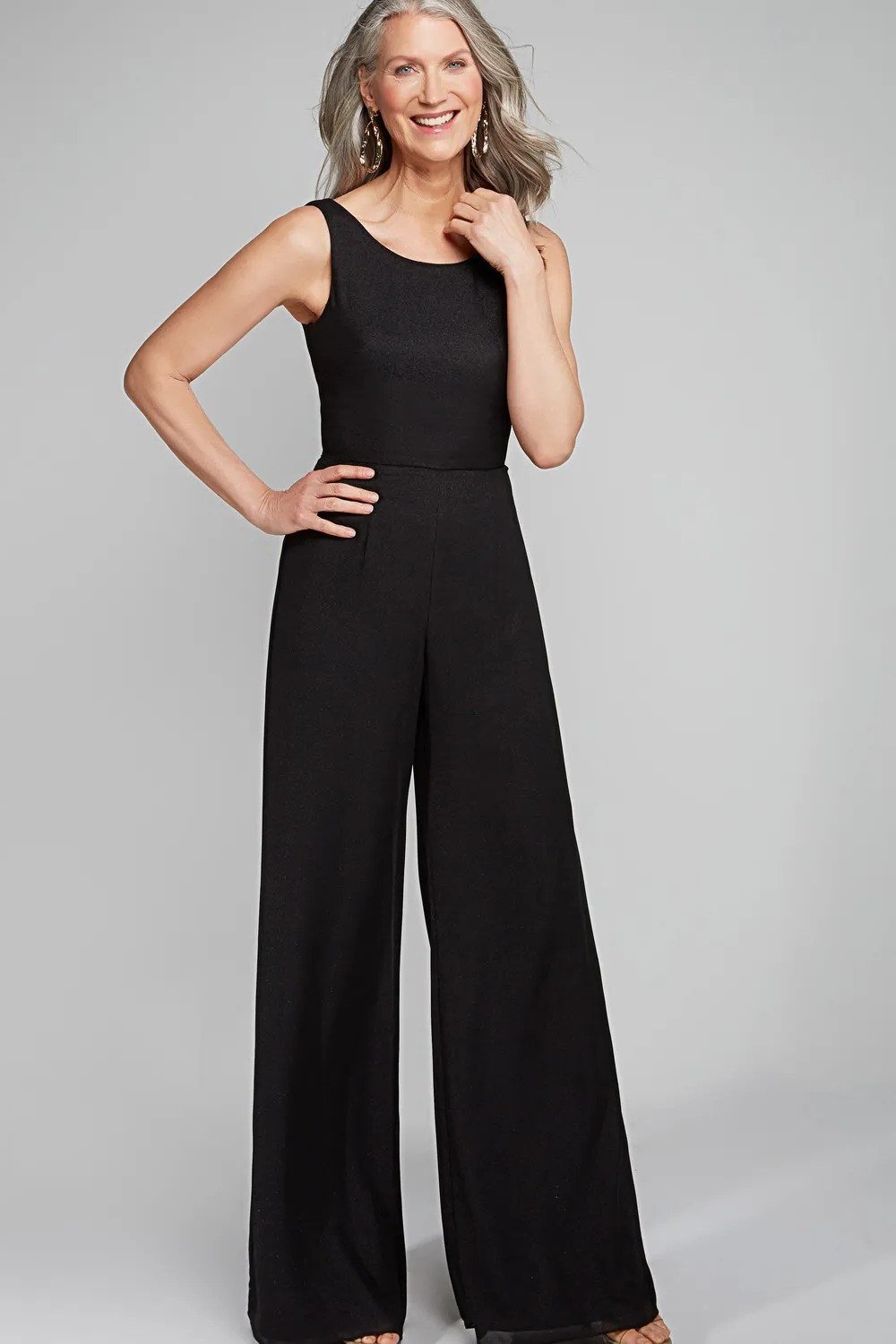 Gray-haired woman in black sleeveless jumpsuit full body, minimalist New Year's Eve jumpsuit for women over 60
