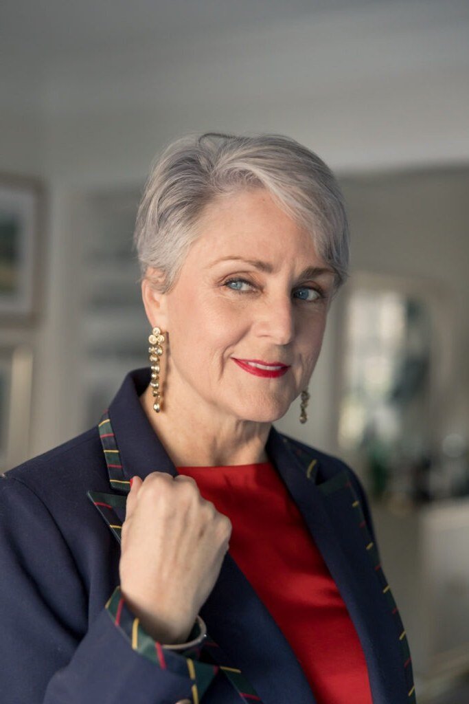 Gray-haired woman in navy blazer over red top portrait, smart New Year's Eve blazer outfit for women over 60