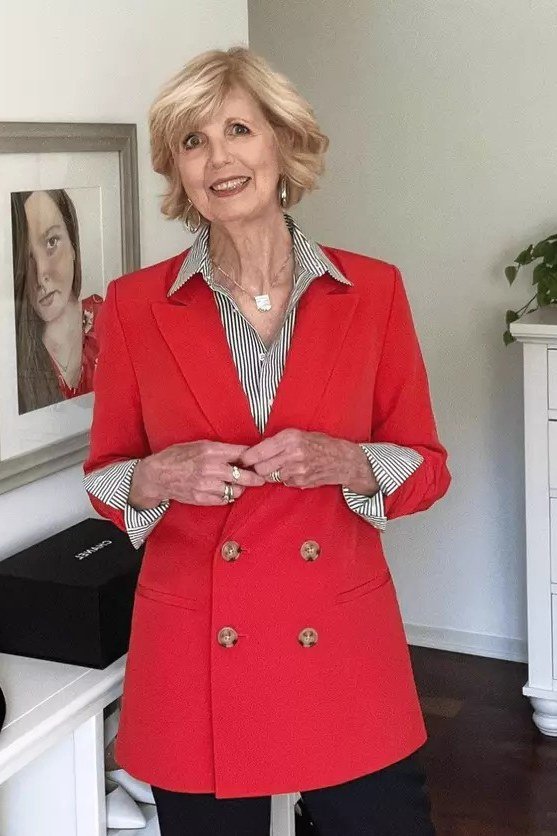 Woman in red double-breasted blazer over striped shirt, confident New Year's Eve blazer outfit for women over 60