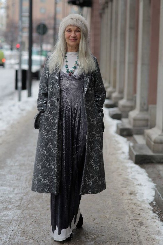 Long gray patterned coat layered over black midi dress with white sneakers, winter outfit for older women