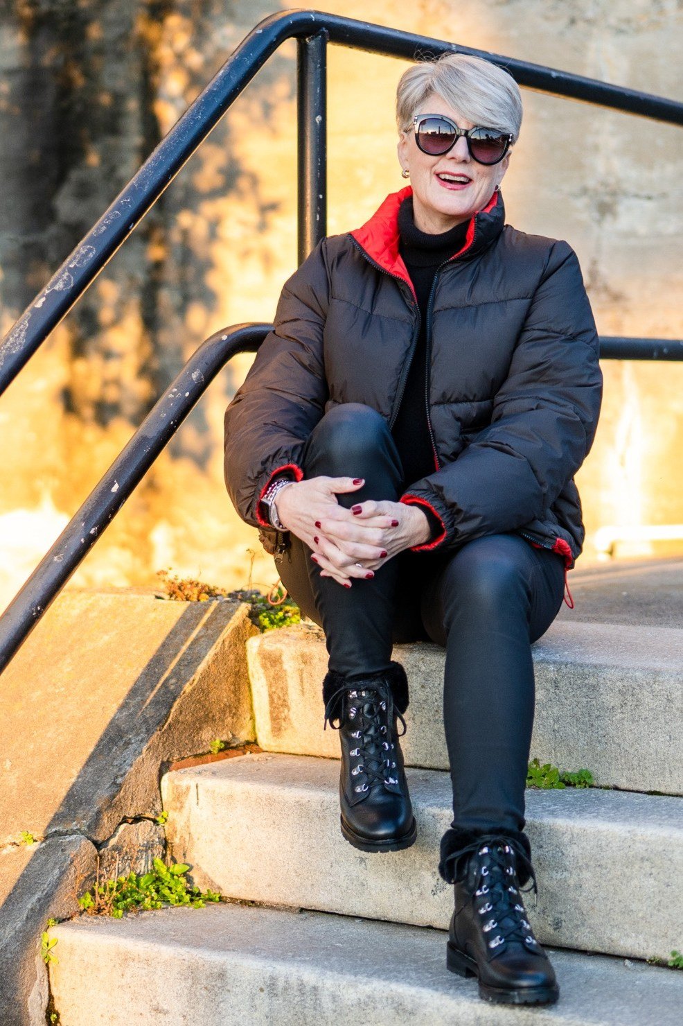 Navy quilted puffer jacket over red turtleneck with black jeans and boots, warm winter outfit for women over 60