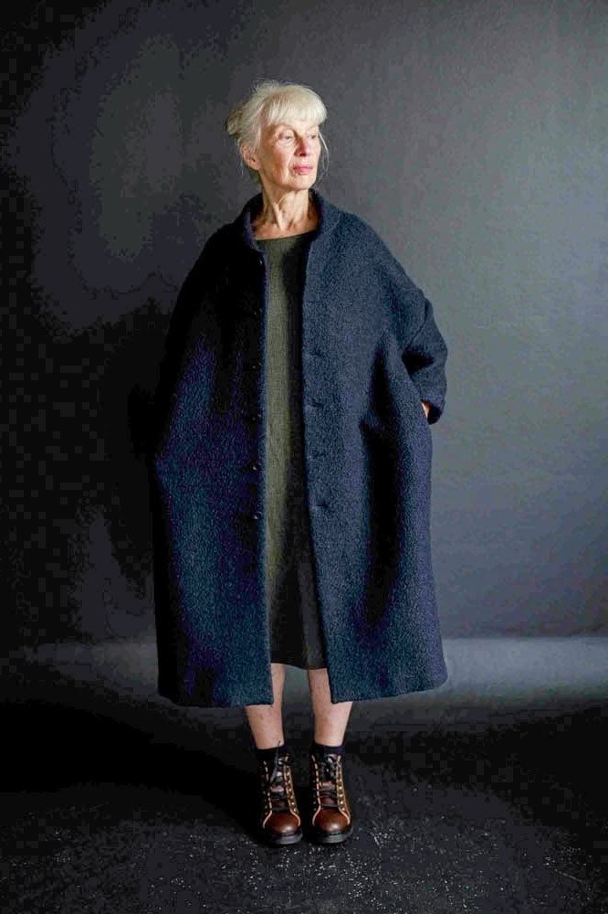 Deep navy wool coat over dark green midi dress with patterned ankle boots, elegant winter outfit for older women
