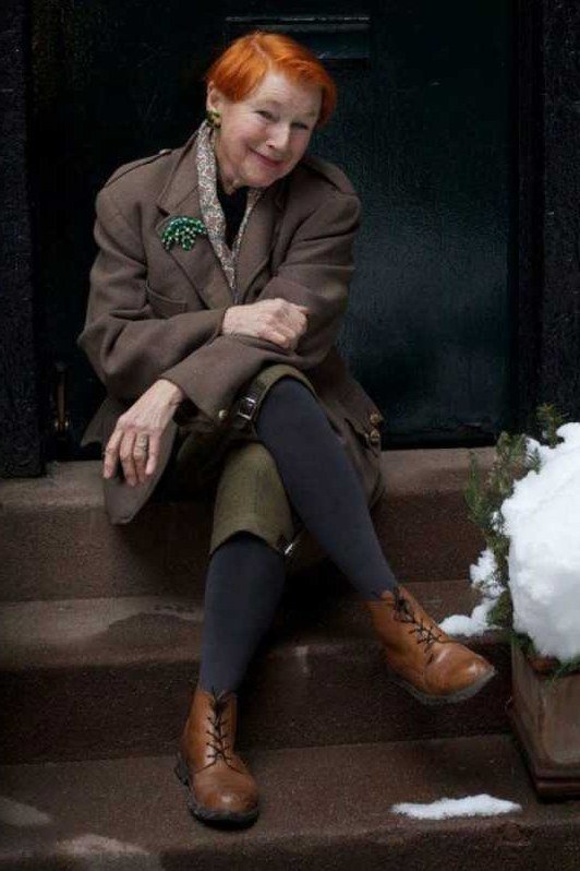 Chocolate brown coat over olive green dress with patterned scarf and tan boots, earthy winter outfit for older women
