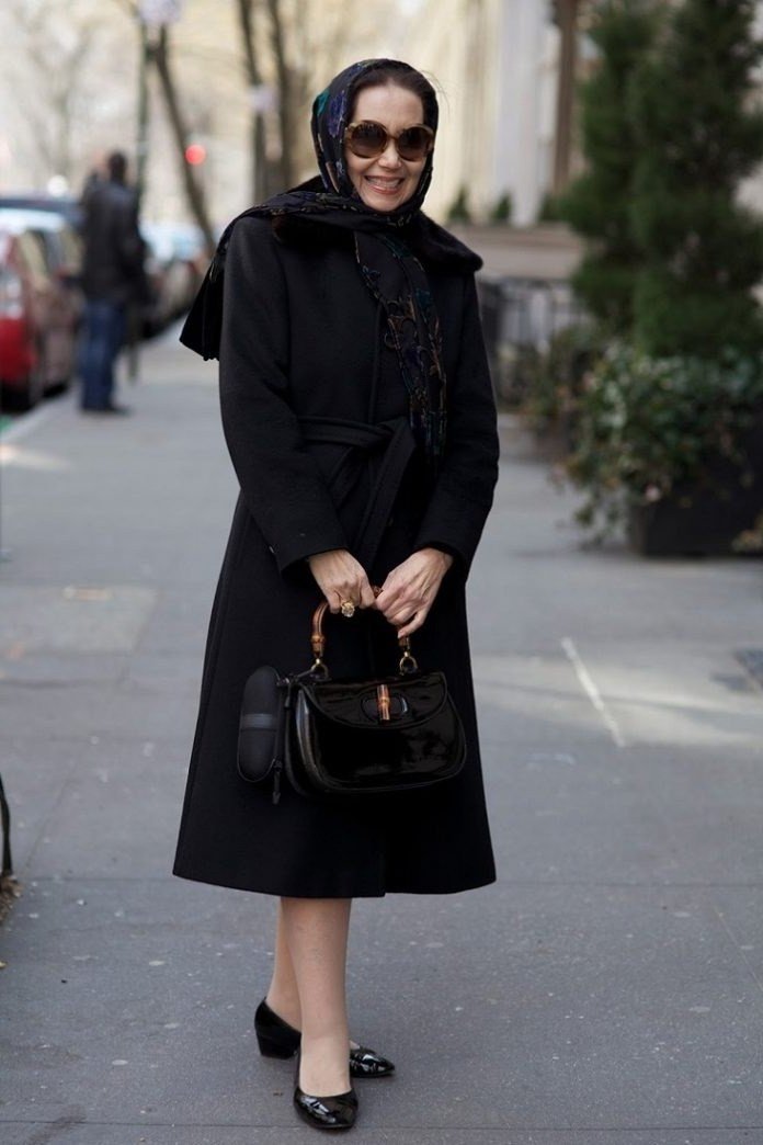 Black wool coat over black midi dress with patterned scarf and heels, all black elegant winter outfit for older women